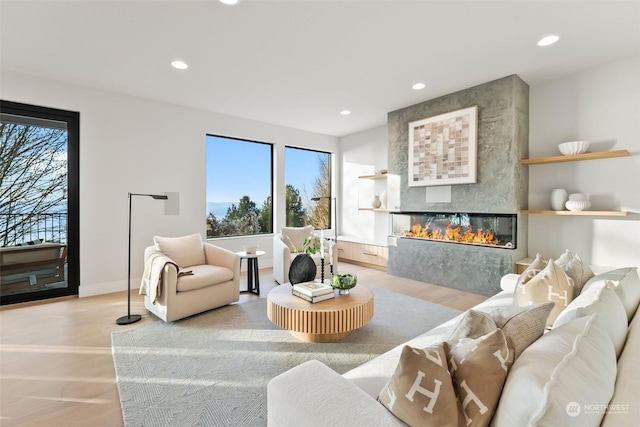 living room featuring a large fireplace, plenty of natural light, and light wood-type flooring