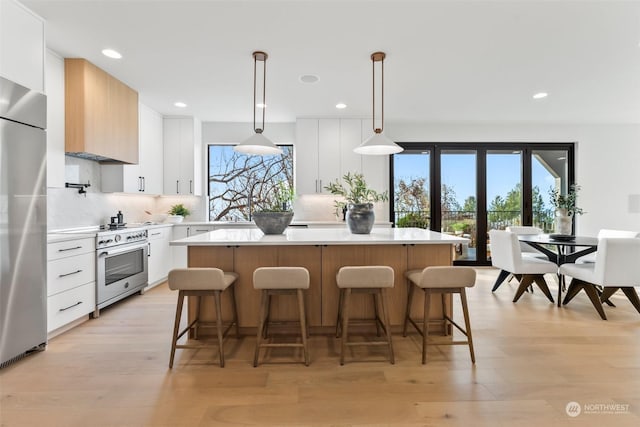 kitchen featuring white cabinets, a center island, decorative light fixtures, and light hardwood / wood-style floors