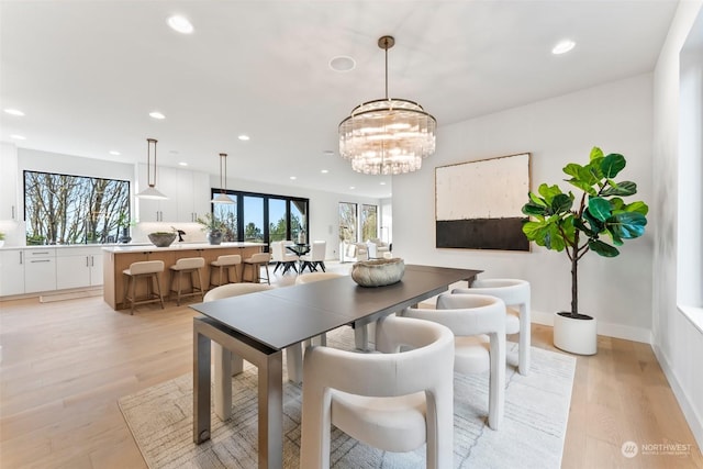 dining space with light hardwood / wood-style flooring and an inviting chandelier