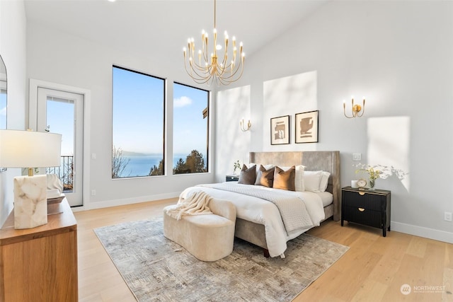 bedroom featuring access to outside, light wood-type flooring, high vaulted ceiling, and an inviting chandelier