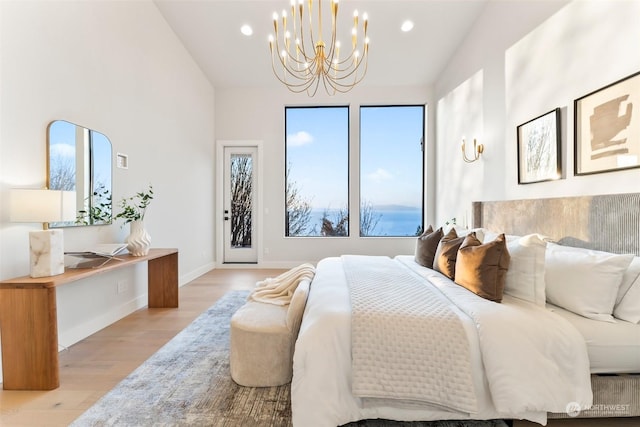 bedroom with access to exterior, light wood-type flooring, a chandelier, and vaulted ceiling