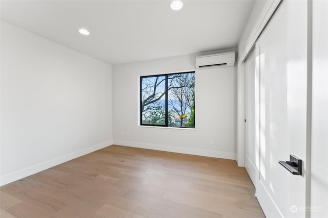 spare room with an AC wall unit and light hardwood / wood-style flooring