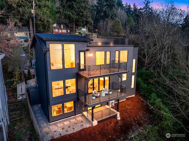 back house at dusk with a balcony