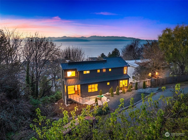 back house at dusk with a water and mountain view