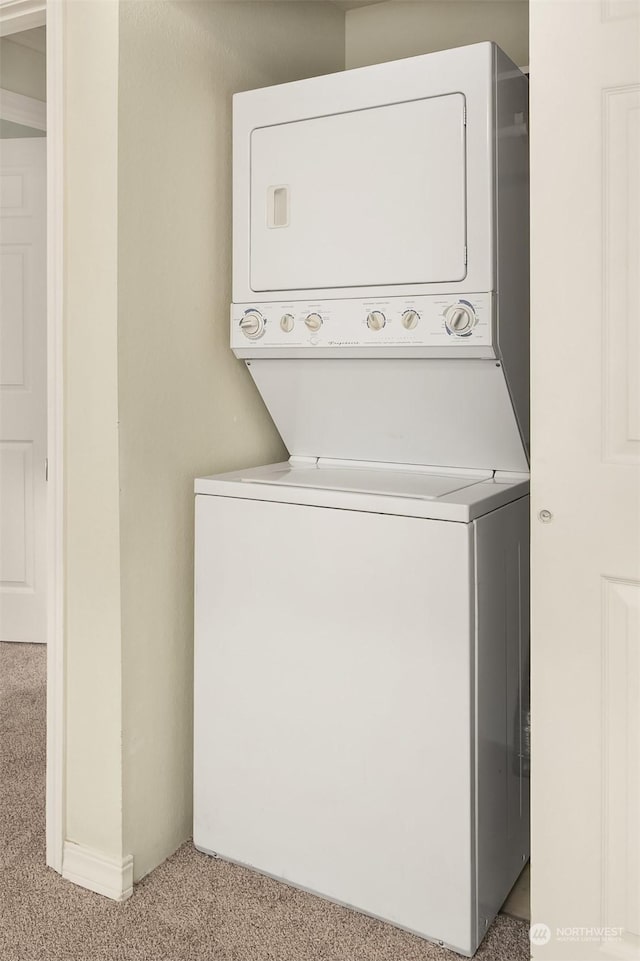 laundry room featuring light colored carpet and stacked washer / drying machine