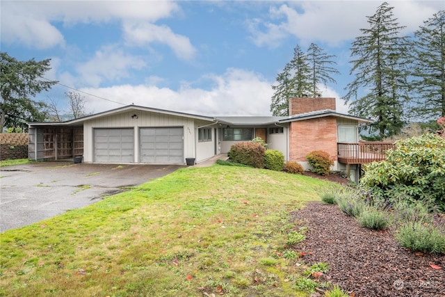 ranch-style home featuring a wooden deck, a front yard, and a garage