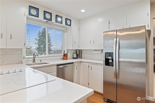 kitchen with white cabinets, decorative backsplash, stainless steel appliances, and sink