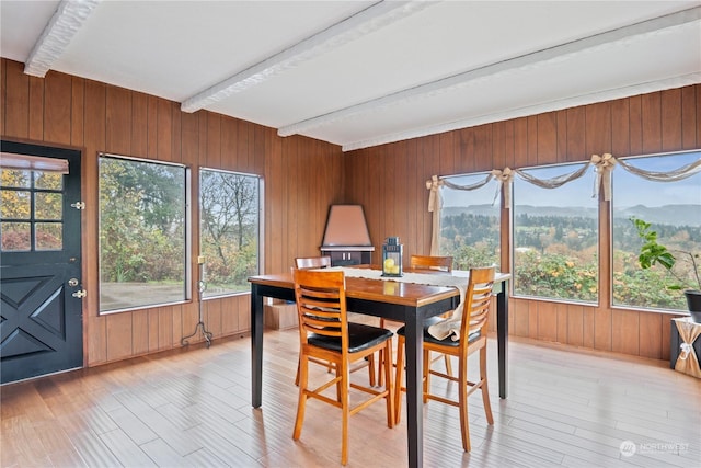 dining space with hardwood / wood-style floors, a mountain view, beam ceiling, and wood walls