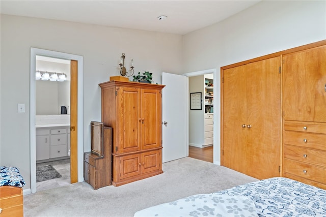 bedroom with connected bathroom, a closet, and light colored carpet