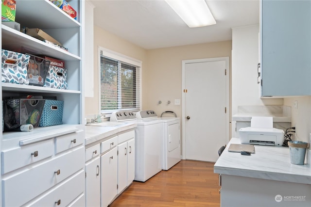 laundry room featuring washing machine and dryer, cabinets, sink, and light hardwood / wood-style floors