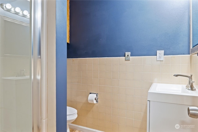 bathroom with vanity, toilet, and tile walls