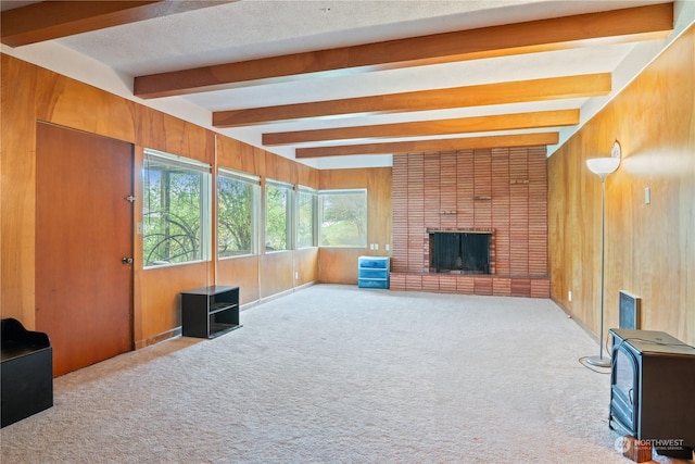 living room featuring beamed ceiling, light colored carpet, a fireplace, and wooden walls