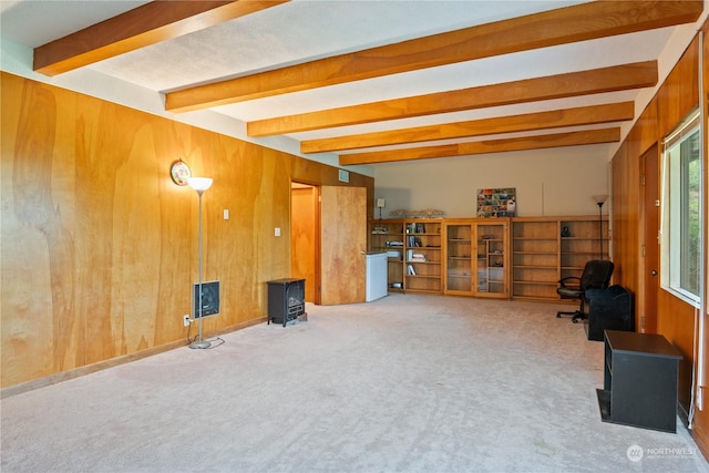 interior space featuring beamed ceiling, carpet floors, a wood stove, and wooden walls