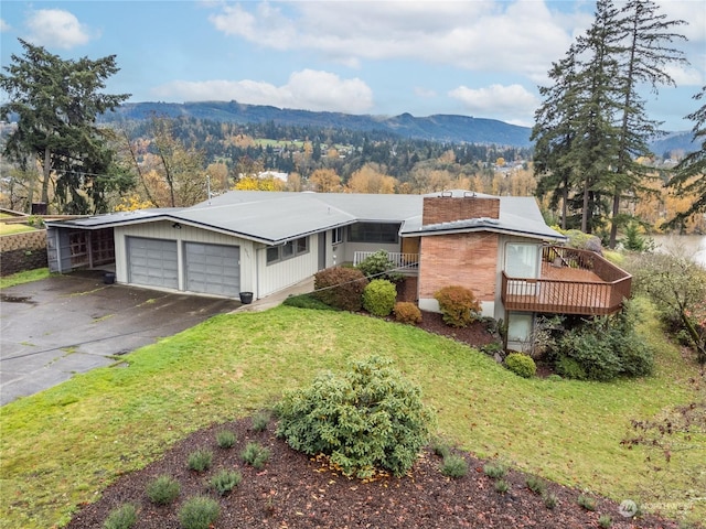 single story home featuring a carport, a deck with mountain view, and a front yard