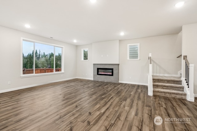 unfurnished living room with a tiled fireplace and wood-type flooring