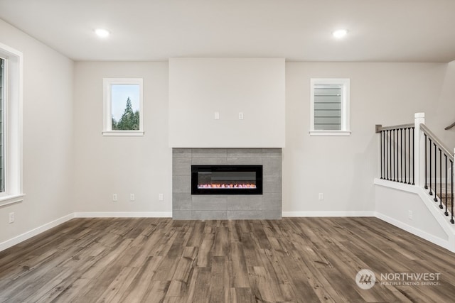 unfurnished living room with hardwood / wood-style floors and a tile fireplace