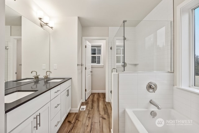 bathroom with hardwood / wood-style flooring, a healthy amount of sunlight, shower with separate bathtub, and vanity