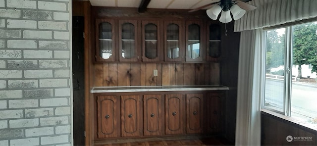 interior space featuring ceiling fan and brick wall