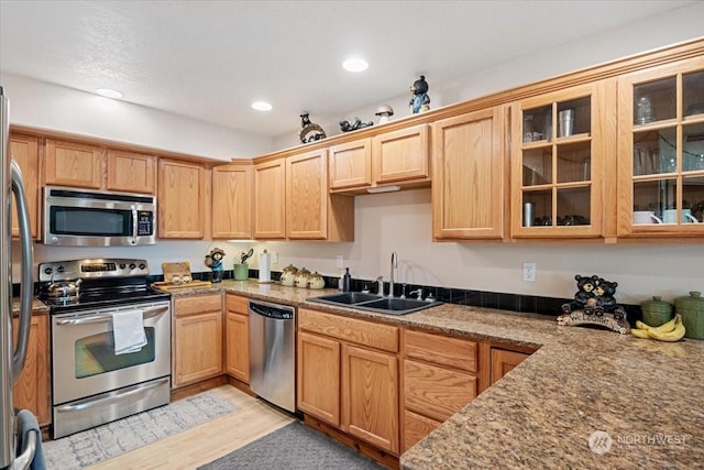 kitchen with light hardwood / wood-style floors, light stone countertops, sink, and appliances with stainless steel finishes