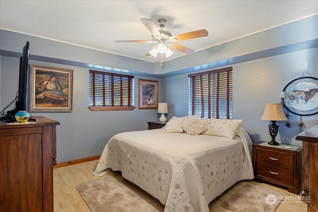 bedroom with multiple windows, light hardwood / wood-style floors, and ceiling fan