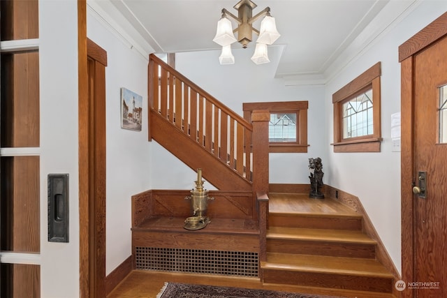 staircase with a notable chandelier and ornamental molding