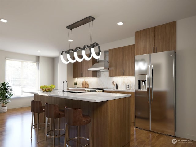 kitchen featuring stainless steel refrigerator with ice dispenser, hanging light fixtures, dark wood-type flooring, and an island with sink