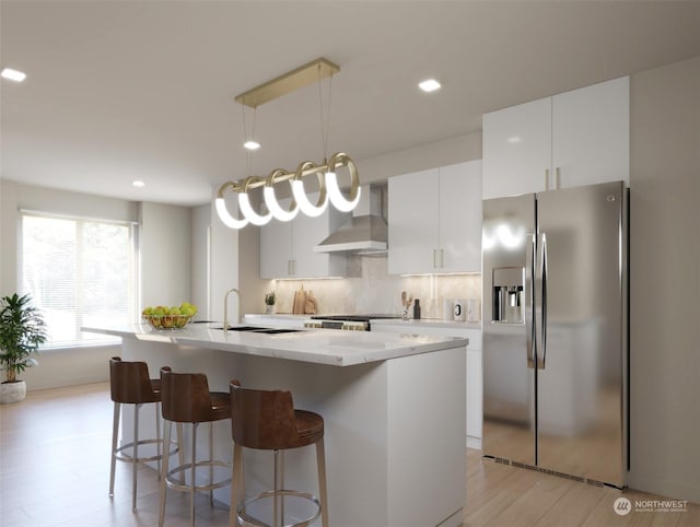 kitchen with white cabinetry, wall chimney range hood, stainless steel refrigerator with ice dispenser, and light hardwood / wood-style flooring