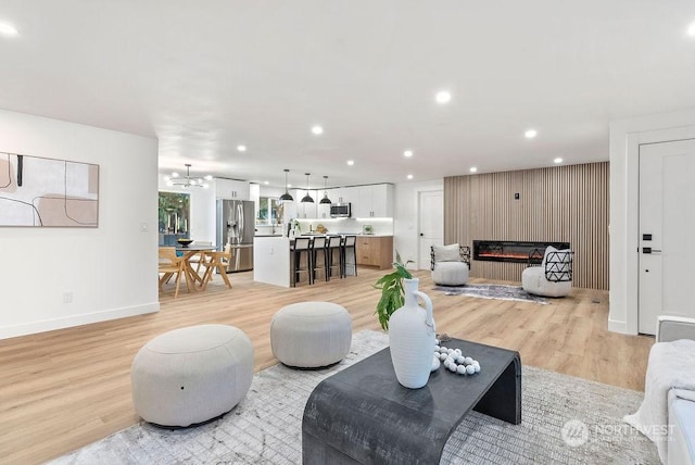 living room featuring a notable chandelier, light hardwood / wood-style floors, and a fireplace