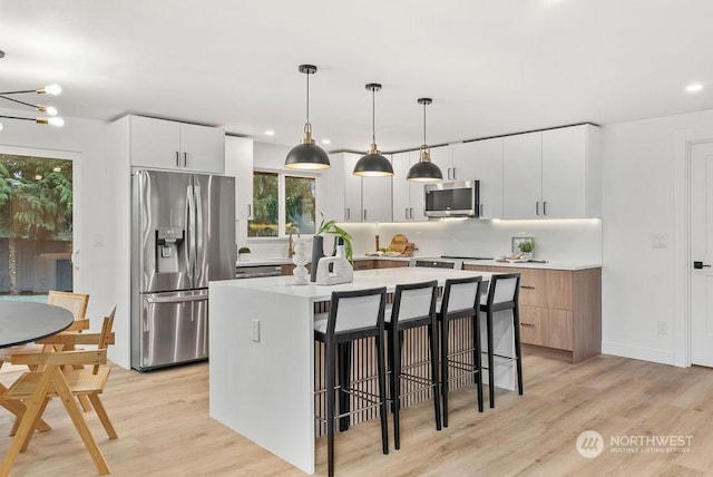 kitchen featuring white cabinets, appliances with stainless steel finishes, a center island, and pendant lighting