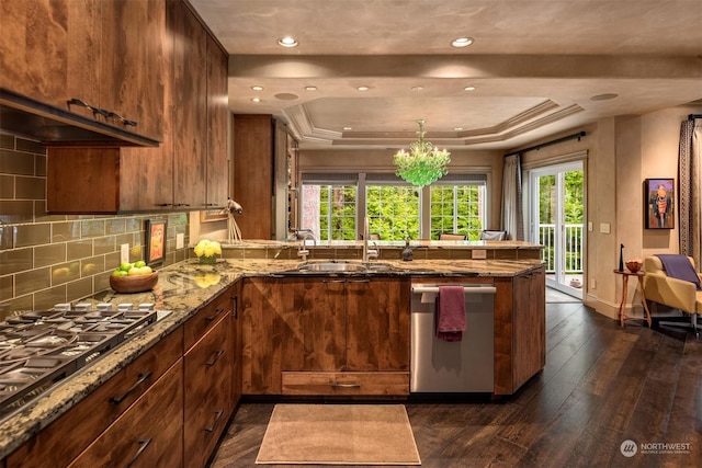 kitchen with decorative backsplash, a raised ceiling, dark wood-style floors, a peninsula, and stainless steel appliances