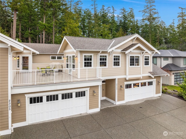 view of property featuring a garage, concrete driveway, and a shingled roof