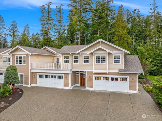 view of front facade featuring a shingled roof, driveway, a balcony, and a garage