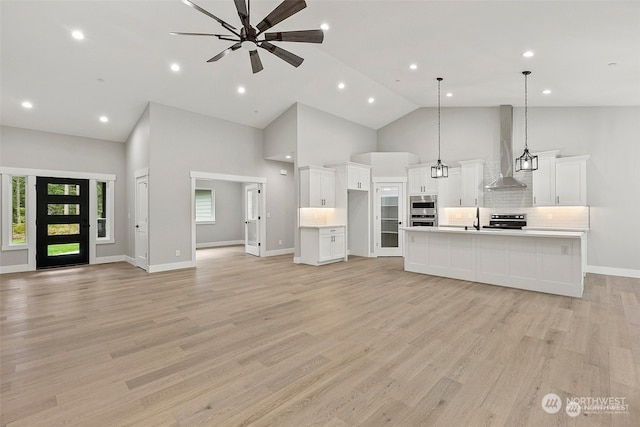 kitchen with decorative light fixtures, high vaulted ceiling, light hardwood / wood-style flooring, white cabinetry, and a large island