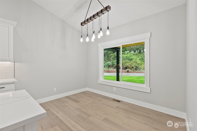 unfurnished dining area with light hardwood / wood-style floors and lofted ceiling