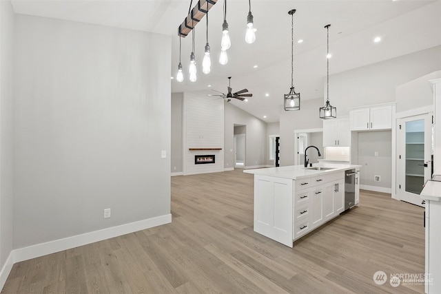 kitchen featuring white cabinetry, sink, high vaulted ceiling, an island with sink, and pendant lighting