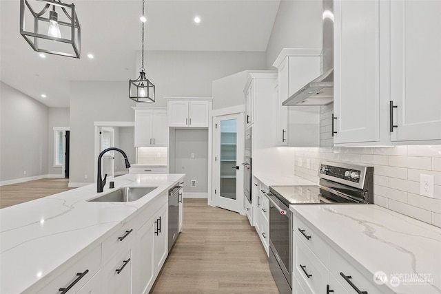 kitchen with sink, hanging light fixtures, stainless steel appliances, wall chimney range hood, and white cabinets