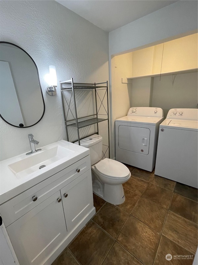 bathroom with tile patterned flooring, washer and dryer, toilet, and vanity