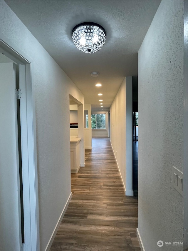 corridor with dark hardwood / wood-style flooring and a textured ceiling