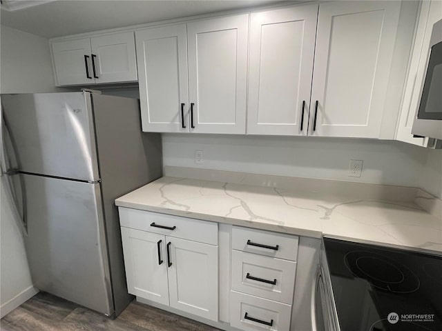 kitchen with white cabinets, dark hardwood / wood-style floors, light stone counters, and stainless steel appliances