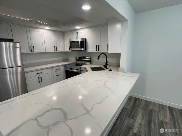 kitchen with light stone counters, stainless steel appliances, white cabinetry, and sink