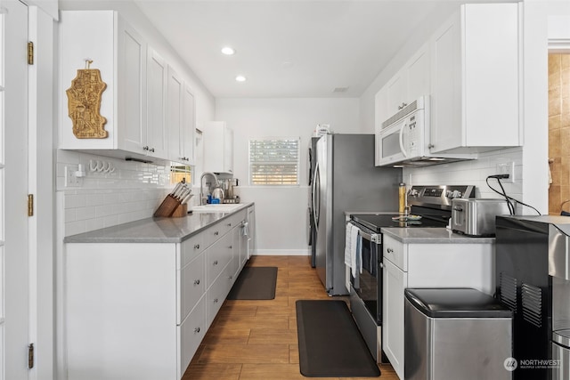 kitchen featuring stainless steel appliances, sink, white cabinets, and decorative backsplash