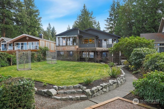 rear view of property featuring a lawn and a sunroom