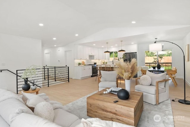 living room featuring light hardwood / wood-style floors, lofted ceiling, and sink