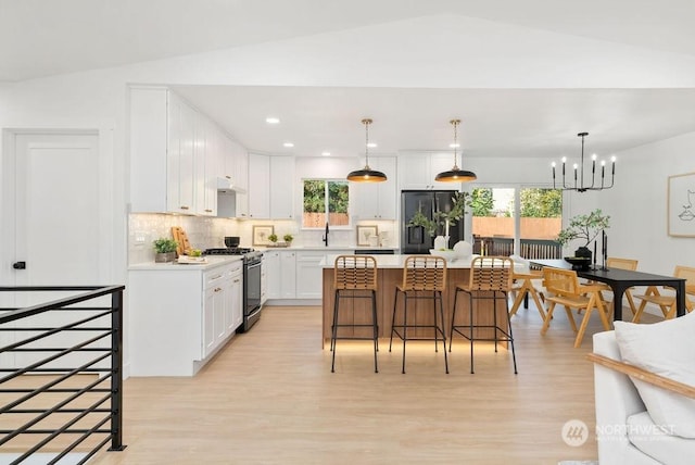 kitchen featuring a center island, stainless steel appliances, hanging light fixtures, and lofted ceiling