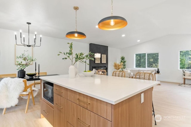 kitchen featuring lofted ceiling, decorative light fixtures, black microwave, and a large island