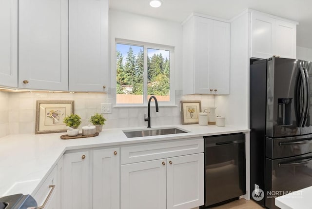 kitchen featuring backsplash, white cabinets, sink, stainless steel fridge, and black dishwasher