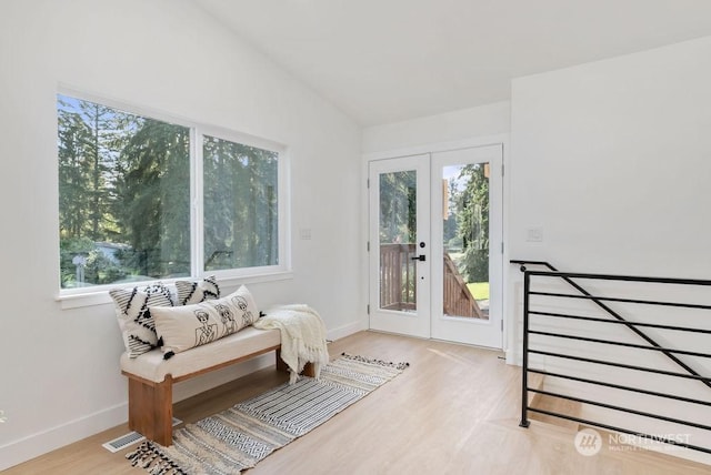 sitting room with french doors, vaulted ceiling, light hardwood / wood-style flooring, and plenty of natural light