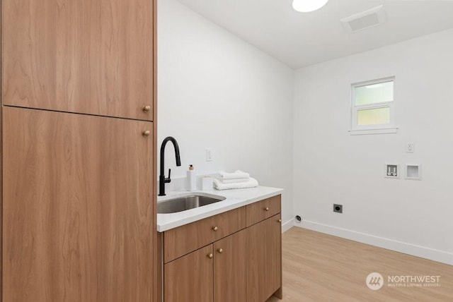 washroom with electric dryer hookup, cabinets, sink, washer hookup, and light wood-type flooring