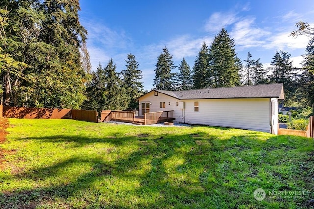 rear view of house with a lawn and a wooden deck