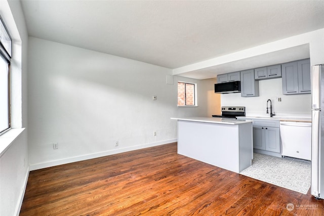 kitchen featuring stainless steel appliances, dark hardwood / wood-style flooring, sink, and gray cabinetry